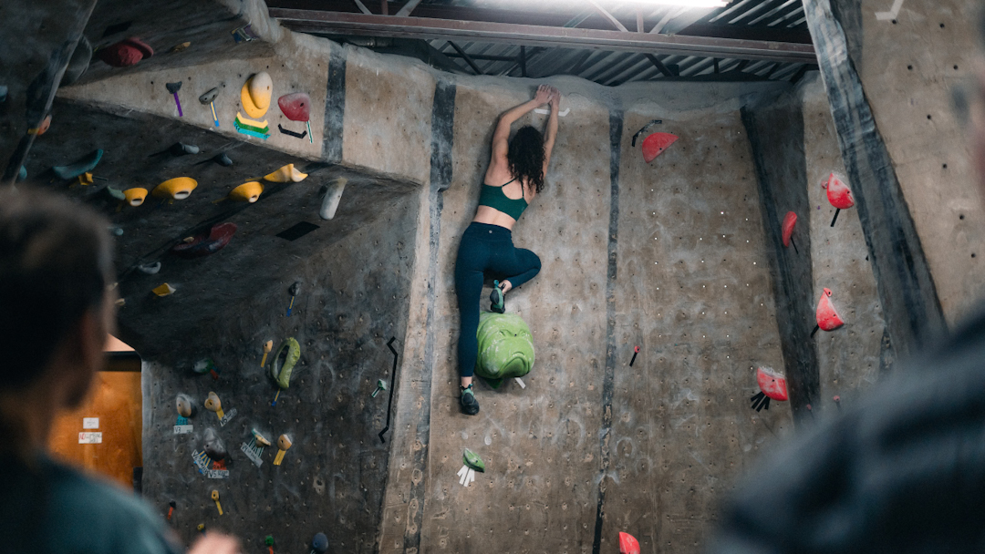 A woman lead climbs a wall at Climbmax rock climbing gym in Tempe